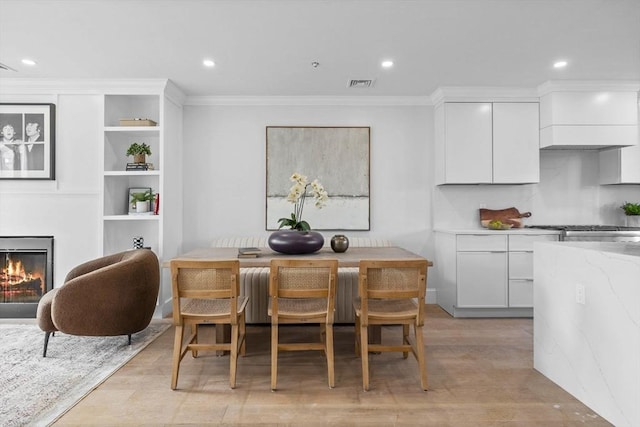 dining area featuring light hardwood / wood-style floors and ornamental molding