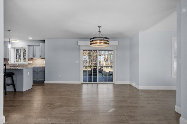 unfurnished dining area featuring sink, dark hardwood / wood-style floors, and an inviting chandelier