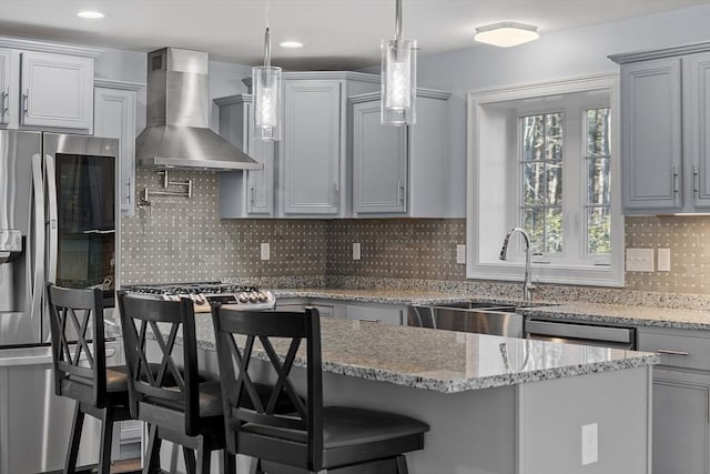 kitchen featuring appliances with stainless steel finishes, tasteful backsplash, a breakfast bar, wall chimney range hood, and decorative light fixtures