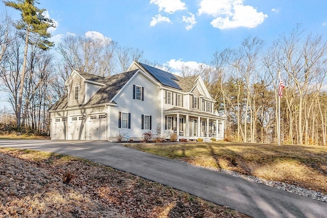 view of front of property featuring covered porch, solar panels, and a garage