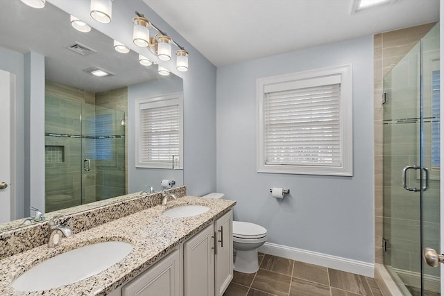 bathroom featuring tile patterned flooring, vanity, toilet, and a shower with shower door