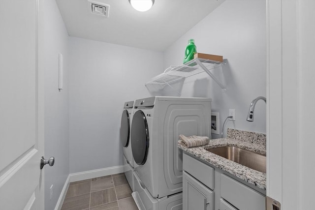 laundry area with cabinets, separate washer and dryer, and sink