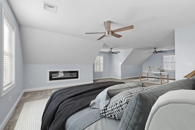 carpeted bedroom with multiple windows, ceiling fan, and vaulted ceiling