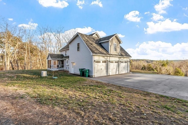 view of side of property featuring a yard, a garage, and a sunroom