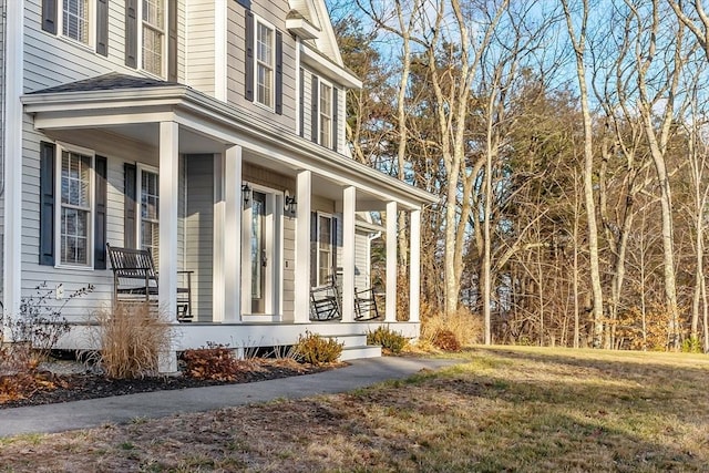 view of side of property featuring a lawn and a porch