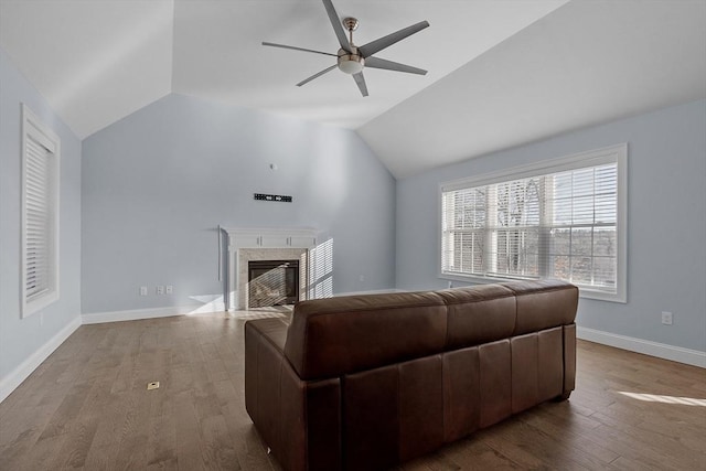 living room with a high end fireplace, wood-type flooring, vaulted ceiling, and ceiling fan