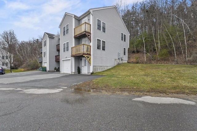 view of home's exterior featuring driveway, a garage, a lawn, and a balcony