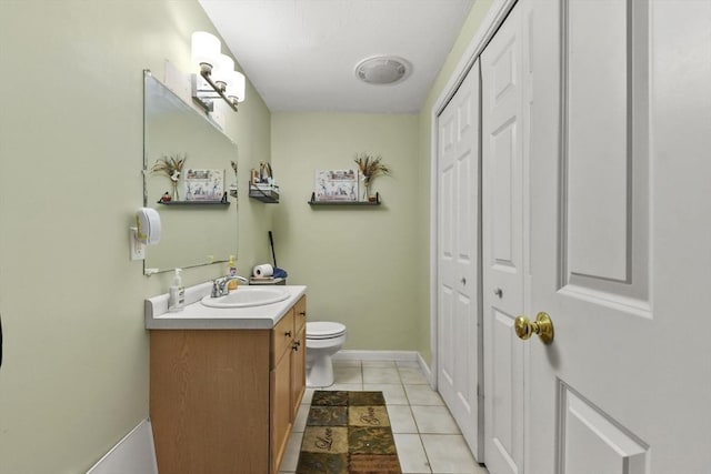 bathroom featuring vanity, a closet, baseboards, tile patterned floors, and toilet