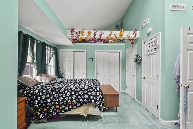 bedroom with baseboards, visible vents, multiple closets, lofted ceiling, and carpet