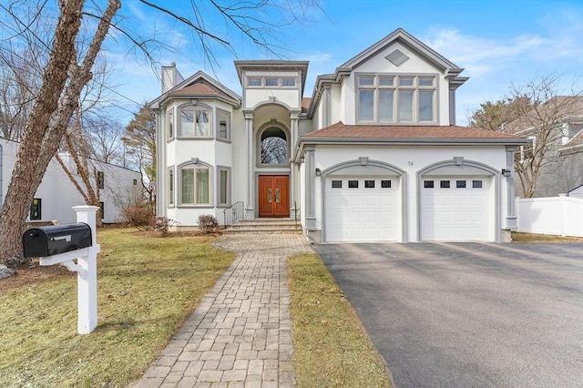 view of front of property with a front yard, fence, stucco siding, a chimney, and aphalt driveway