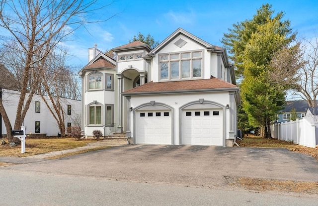 view of front of home with aphalt driveway, stucco siding, a chimney, and fence