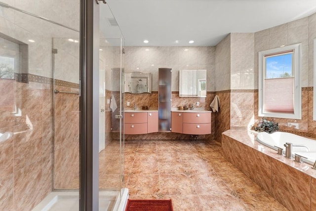 full bath with a stall shower, recessed lighting, tile walls, a bath, and vanity