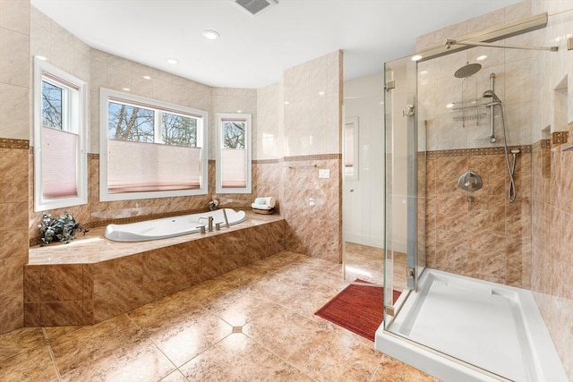 full bath with visible vents, a shower stall, tile walls, and a garden tub