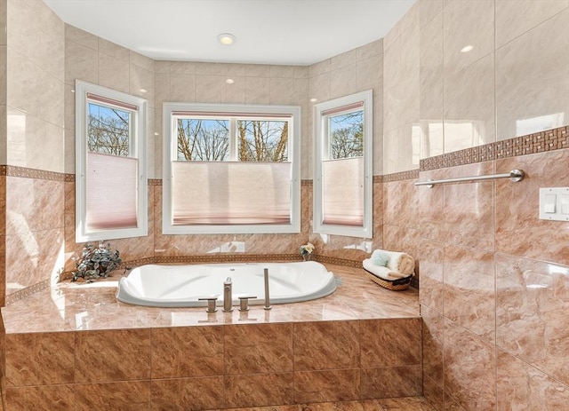 bathroom with a garden tub and tile walls