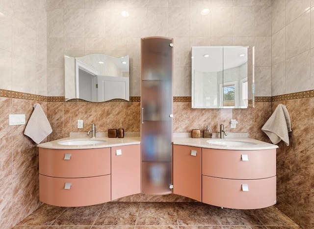 full bath with tile walls, two vanities, and a sink