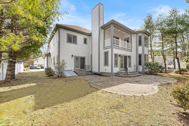 back of property featuring entry steps, a chimney, and a balcony