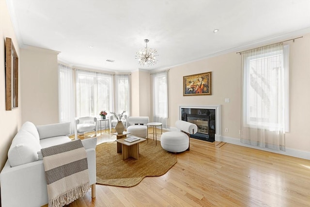 living area with wood finished floors, baseboards, a high end fireplace, ornamental molding, and a notable chandelier