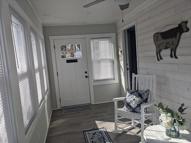 interior space featuring wooden walls, dark hardwood / wood-style flooring, ceiling fan, and a healthy amount of sunlight