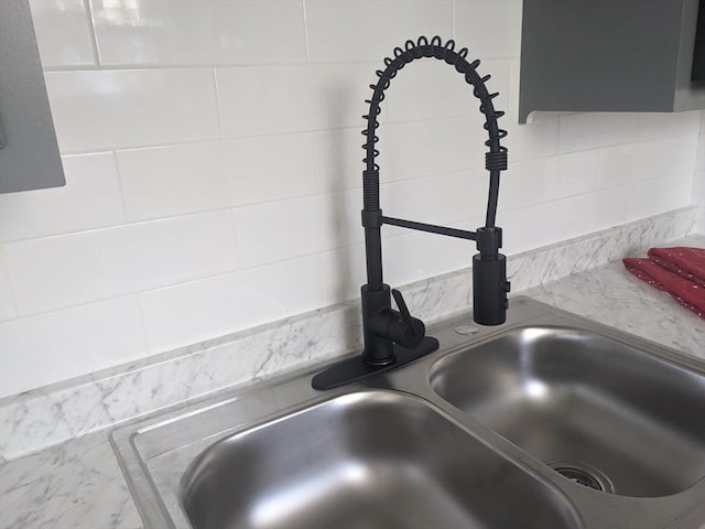 interior details with backsplash, white cabinetry, and sink