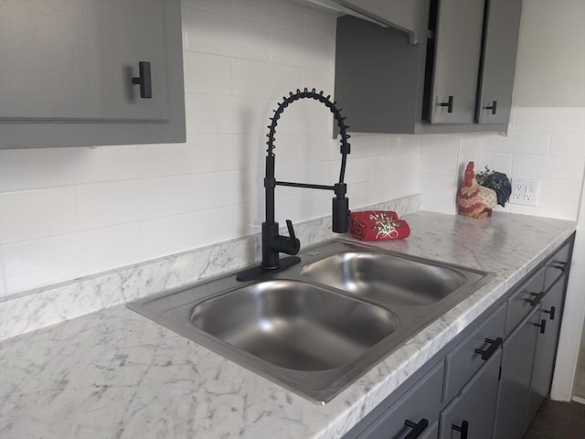 kitchen with backsplash, gray cabinetry, and sink