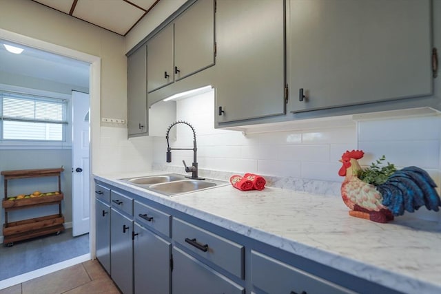 kitchen with backsplash, gray cabinetry, sink, and light tile patterned floors