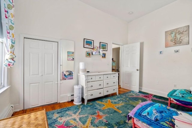 bedroom with baseboard heating, wood finished floors, and baseboards