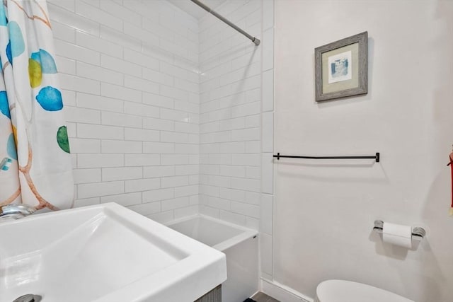 full bathroom with a sink, a shower with curtain, toilet, and baseboards
