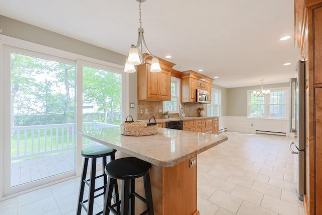 kitchen featuring a chandelier, stainless steel appliances, a peninsula, a sink, and a breakfast bar area