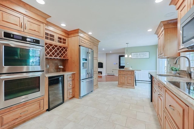 kitchen with appliances with stainless steel finishes, beverage cooler, light brown cabinets, a sink, and recessed lighting