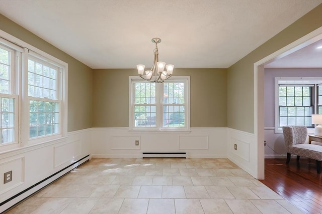 unfurnished dining area with a baseboard radiator, a baseboard heating unit, healthy amount of natural light, a chandelier, and a wainscoted wall