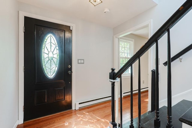 foyer with wood finished floors, stairway, a baseboard heating unit, and baseboards