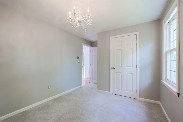unfurnished bedroom with a chandelier, light carpet, baseboards, and multiple windows