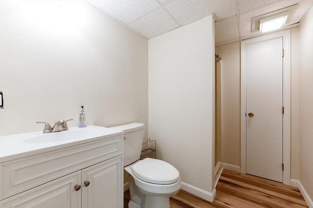 full bathroom featuring wood finished floors, toilet, a drop ceiling, a shower with shower curtain, and vanity