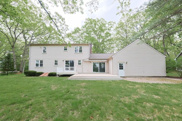 back of property featuring a wooden deck and a lawn