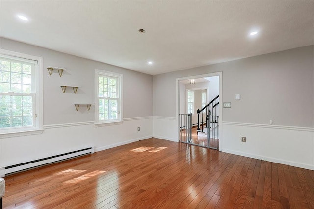 empty room with plenty of natural light, hardwood / wood-style flooring, stairway, and recessed lighting