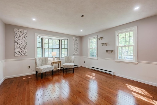living area featuring a baseboard heating unit, wood-type flooring, recessed lighting, and baseboards