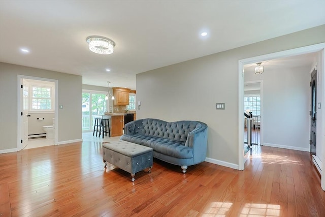living area featuring baseboard heating, light wood-style floors, baseboards, and recessed lighting
