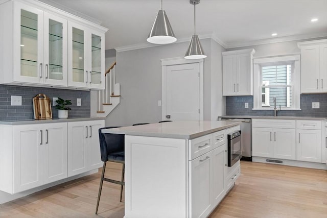 73 Knoll St Unit 73, Boston, MA 02131 - kitchen featuring ornamental molding, tasteful backsplash, light wood-style floors, glass insert cabinets, and white cabinetry