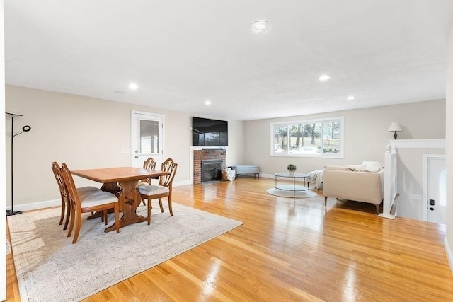 dining room featuring recessed lighting, a fireplace, light wood-type flooring, and baseboards