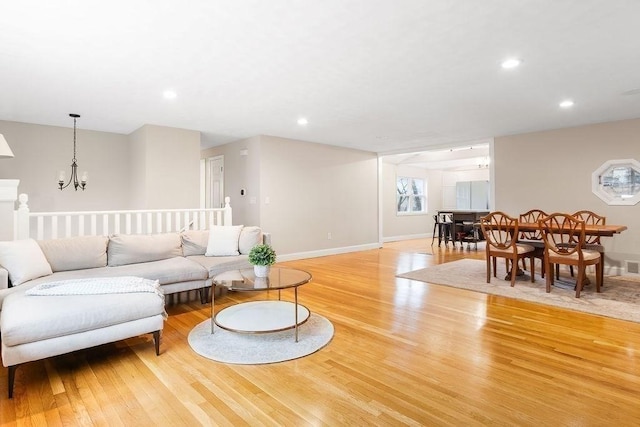 living room with a notable chandelier, recessed lighting, light wood-type flooring, and baseboards