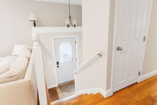 foyer with light wood-type flooring, baseboards, and a chandelier