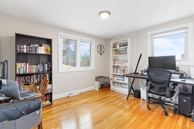 office space with wood finished floors, visible vents, and a healthy amount of sunlight