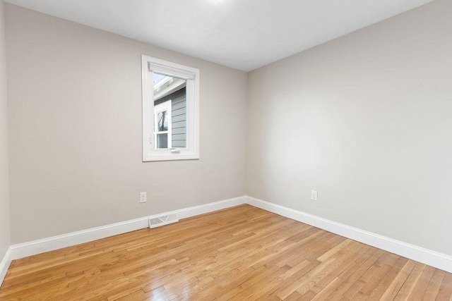 empty room with light wood-style flooring, baseboards, and visible vents