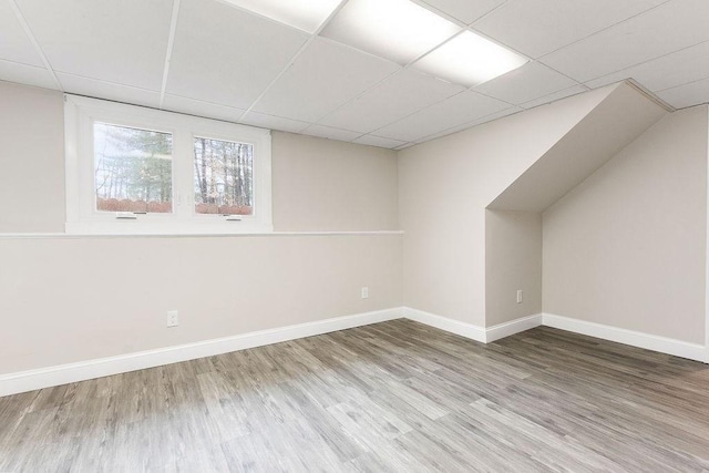 additional living space with baseboards and wood finished floors