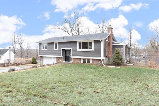 bi-level home with a front lawn, a garage, and a chimney