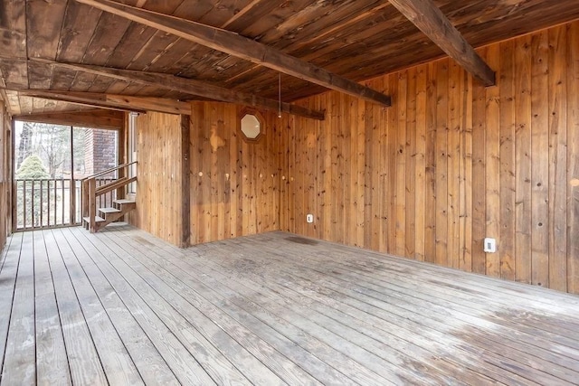 empty room featuring beamed ceiling, wooden walls, wood ceiling, and hardwood / wood-style floors