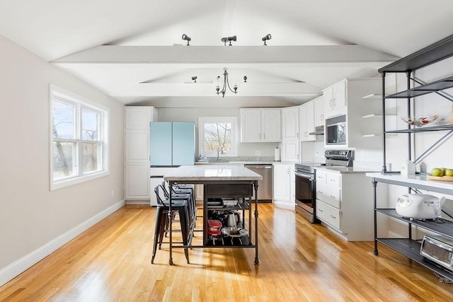 kitchen featuring white cabinetry, baseboards, appliances with stainless steel finishes, and a sink