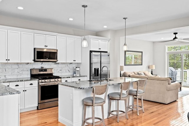 54 Sunflower Way, Plymouth, MA 02360 - kitchen with stainless steel appliances, open floor plan, a sink, light wood-style flooring, and light stone countertops