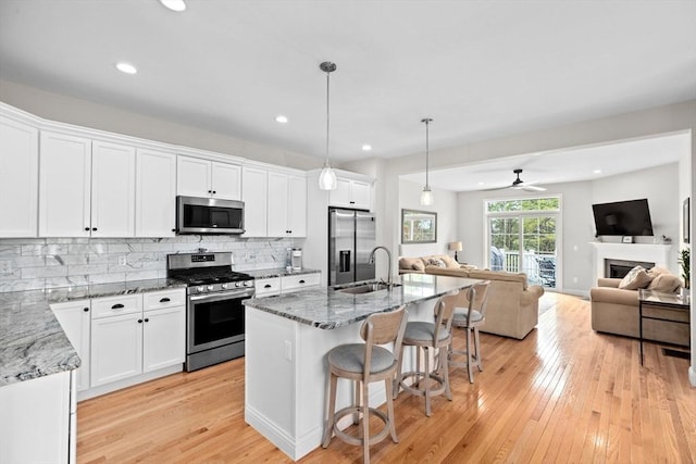 54 Sunflower Way, Plymouth, MA 02360 - kitchen featuring appliances with stainless steel finishes, open floor plan, light wood-type flooring, light stone counters, and a sink