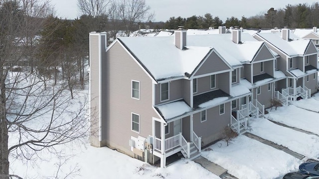 snow covered back of property featuring a residential view and a chimney